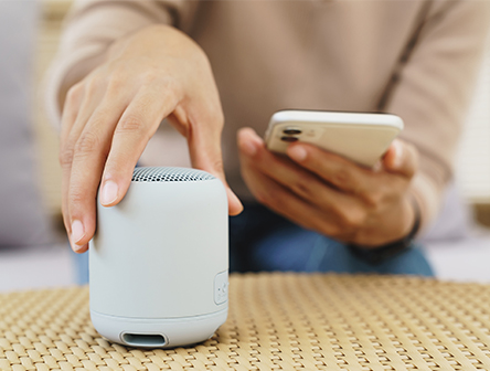A person connecting their phone to a Bluetooth speaker