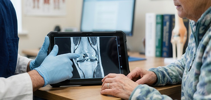 A patient with a doctor lookin at a scan on a tablet device